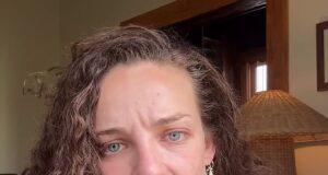 Upset woman with curly hair and blue eyes in a polka dot dress, indoors, emotional expression.