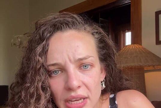 Upset woman with curly hair and blue eyes in a polka dot dress, indoors, emotional expression.