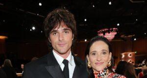 Elegant woman in a vibrant patterned dress standing next to man in a sharp black suit at a formal event.