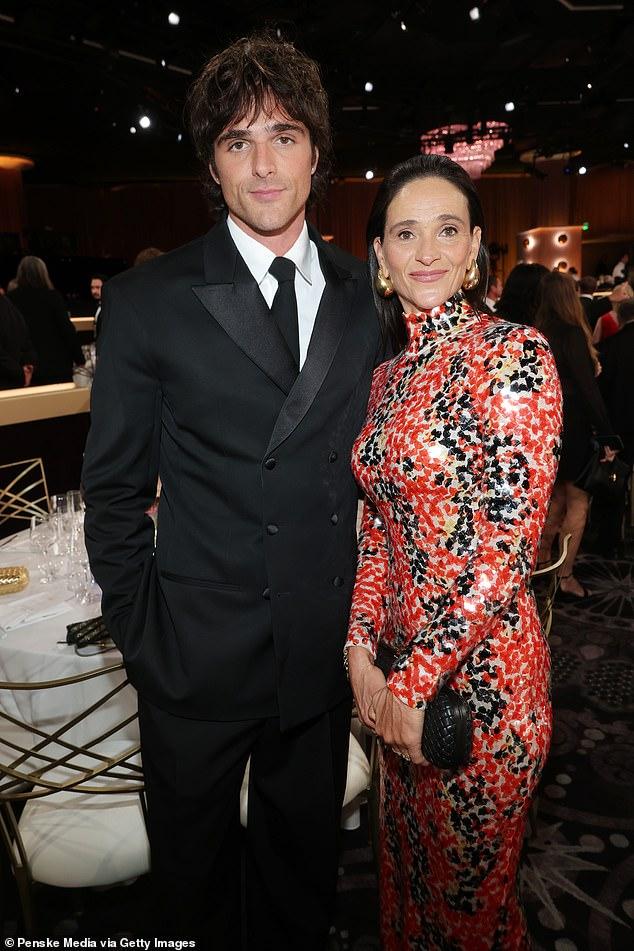 News Room : Awkward moment Jacob Elordi's mother snubs Leonardo Elegant woman in a vibrant patterned dress standing next to man in a sharp black suit at a formal event.