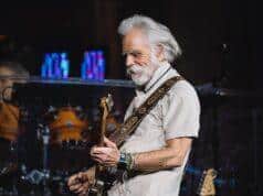OLD MAN PLAYING GUITAR AT CONCERT, MUSICIAN PERFORMING ON STAGE.