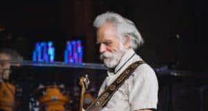 OLD MAN PLAYING GUITAR AT CONCERT, MUSICIAN PERFORMING ON STAGE.
