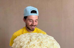 News Room : Brooklyn Beckham copies estranged dad David as he celebrates wife Nicola Peltz’s birthday in same way footballer marked Victoria’s – after the heiress deleted all trace of her in-laws from Instagram Vase filled with white roses held by smiling man wearing baseball cap.
