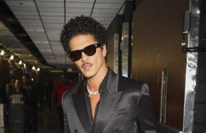 News Room : Bruno Mars breaks record for most tickets sold in a single day ahead of his hotly-anticipated new tour Stylish man in black satin double-breasted suit with sunglasses at airport.