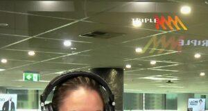 Woman broadcasting live at a radio station studio in a modern office environment.