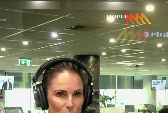 Woman broadcasting live at a radio station studio in a modern office environment.