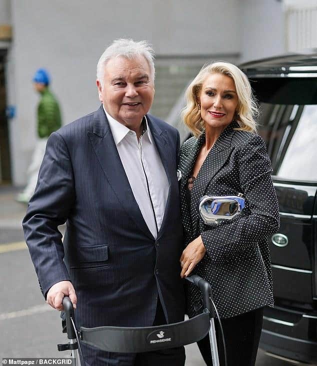 News Room : Eamonn Holmes, 66, 'purchases new pad for Elderly man with walker and woman in formal attire smiling outdoors.