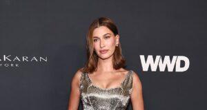 Elegant woman in gold metallic dress at event, posing on red carpet.