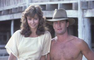 News Room : Inside The Thorn Birds’ Rachel Ward’s four-decade love story with co-star Bryan Brown, 78, and the secret to their long-lasting marriage – after actress, 68, responded to cruel trolling over her looks Young woman and shirtless man standing outdoors on wooden structure in vintage attire.
