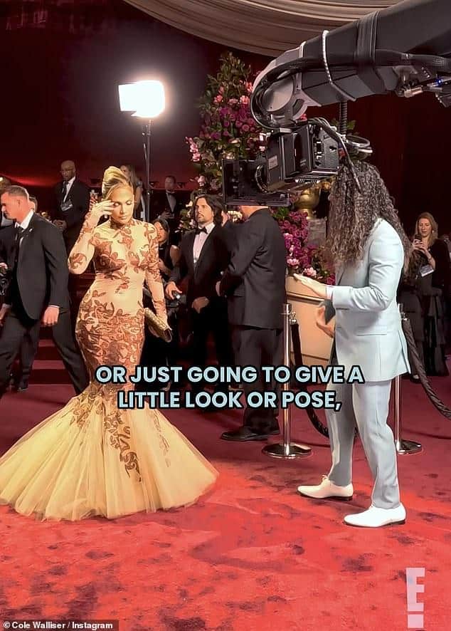 News Room : Jennifer Lopez's 'rude' Glambot moment explained as Elegant woman in glamorous gown being filmed at red carpet event with professional camera crew.
