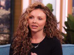 Curly-haired woman speaking passionately on a talk show set.