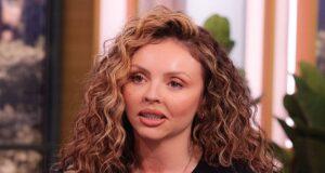 Curly-haired woman speaking passionately on a talk show set.