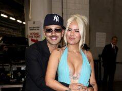 Smiling couple embracing at an indoor event, woman in a striking blue gown with thigh-high slit.