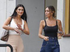 Women having conversation outside a building in casual attire, one gesturing with her hand.