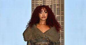 Stylish woman in a textured coat, patterned tights, and fur boots on city rooftop balcony at sunset.