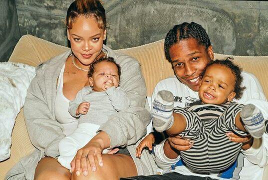 Happy family with young children smiling, sitting on a sofa indoors.