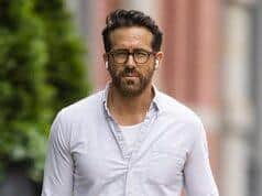 Stylish man walking outdoors in casual attire on city street.