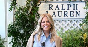 Elegant woman in Ralph Lauren outfit at shopping mall or boutique, smiling and holding a handbag.