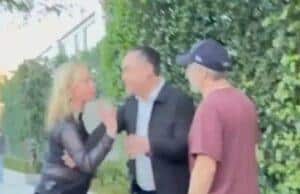 Distressed woman arguing with man on sidewalk, angry confrontation outside house, tension between individuals over a dispute.