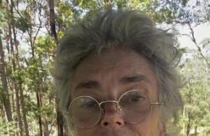 News Room : Thorn Birds star Rachel Ward, 68, fires back at her critics after being viciously trolled for sharing no make-up selfie: ‘I don’t regret losing my youth and beauty – ageing is to be exalted!’ Elderly woman with glasses and floral blouse outdoors in sunny forest setting.