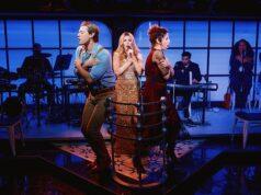 Performers on stage during a theatrical show in a vibrant, modern setting with live musicians in the background.