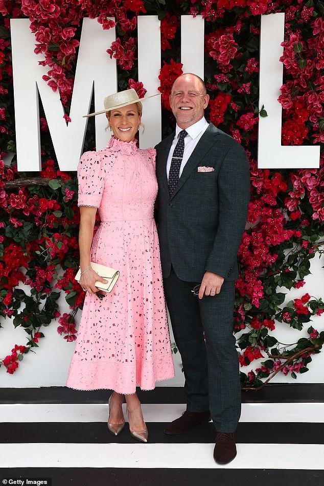 News Room : Zara Tindall is the picture of elegance Elegant woman in pink dress with hat, standing with man in dark suit at floral backdrop event.